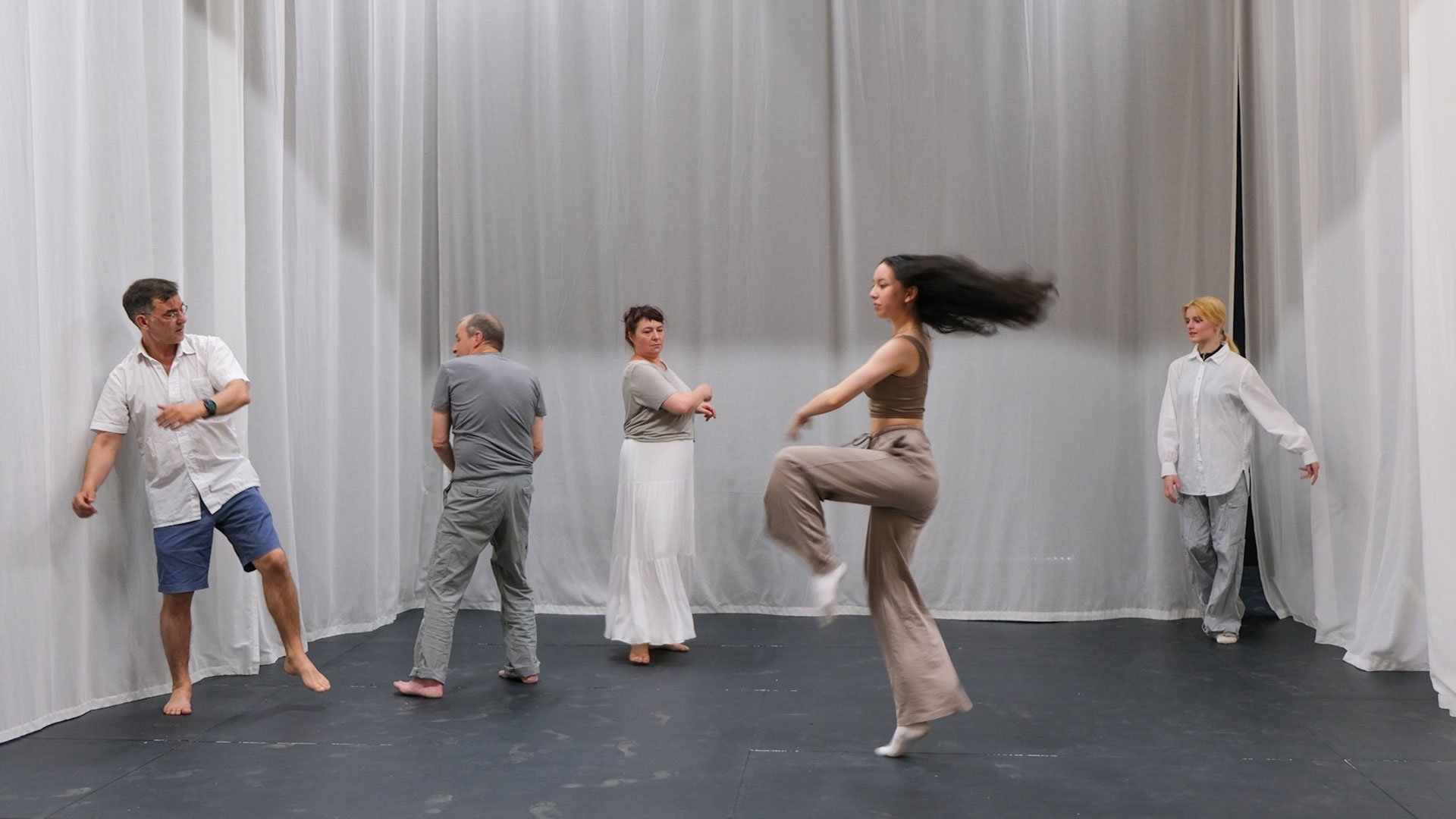 Eventfoto „IN MEMORIAM – Der Mensch, das Spiel der Zeit“ mit fünf Personen in einem Raum mit weißen Vorhängen.