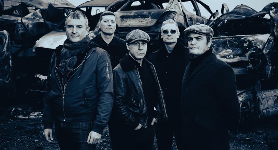 Ein Foto der Band auf einem Autofriedhof. Das Foto ist in Schwarz-Weiß.