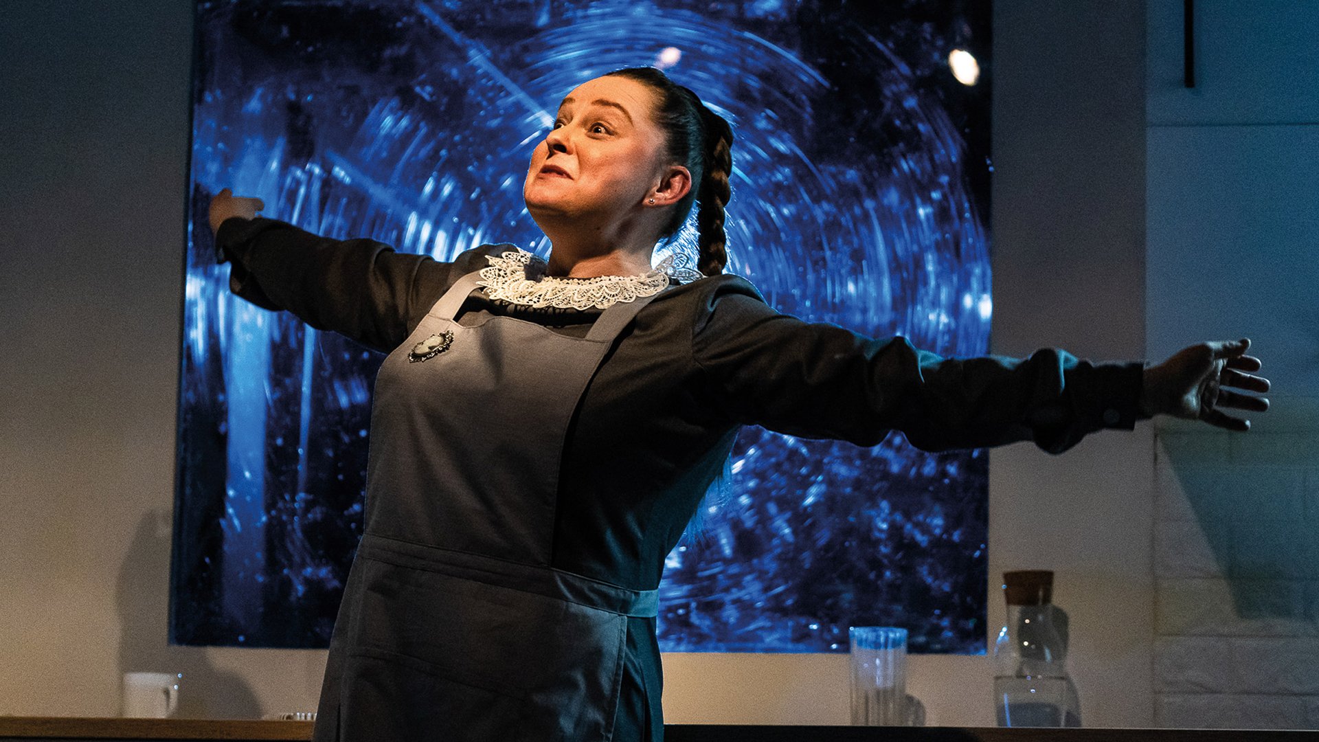 Foto für die Veranstaltung „Soloway 2026 – Squirrel, who has lived for 100 years“ mit einer Darstellerin in Dienstmädchenkostüm mit ausgebreiteten Armen.