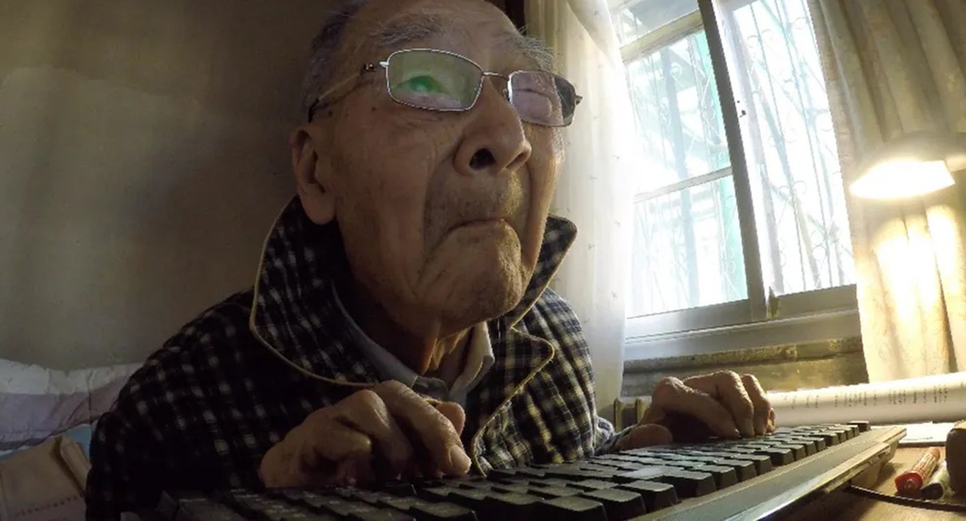 EIn älterer Herr mit Brille blickt suchend in einen Bildschirm mit den Händen auf einer Tastatur