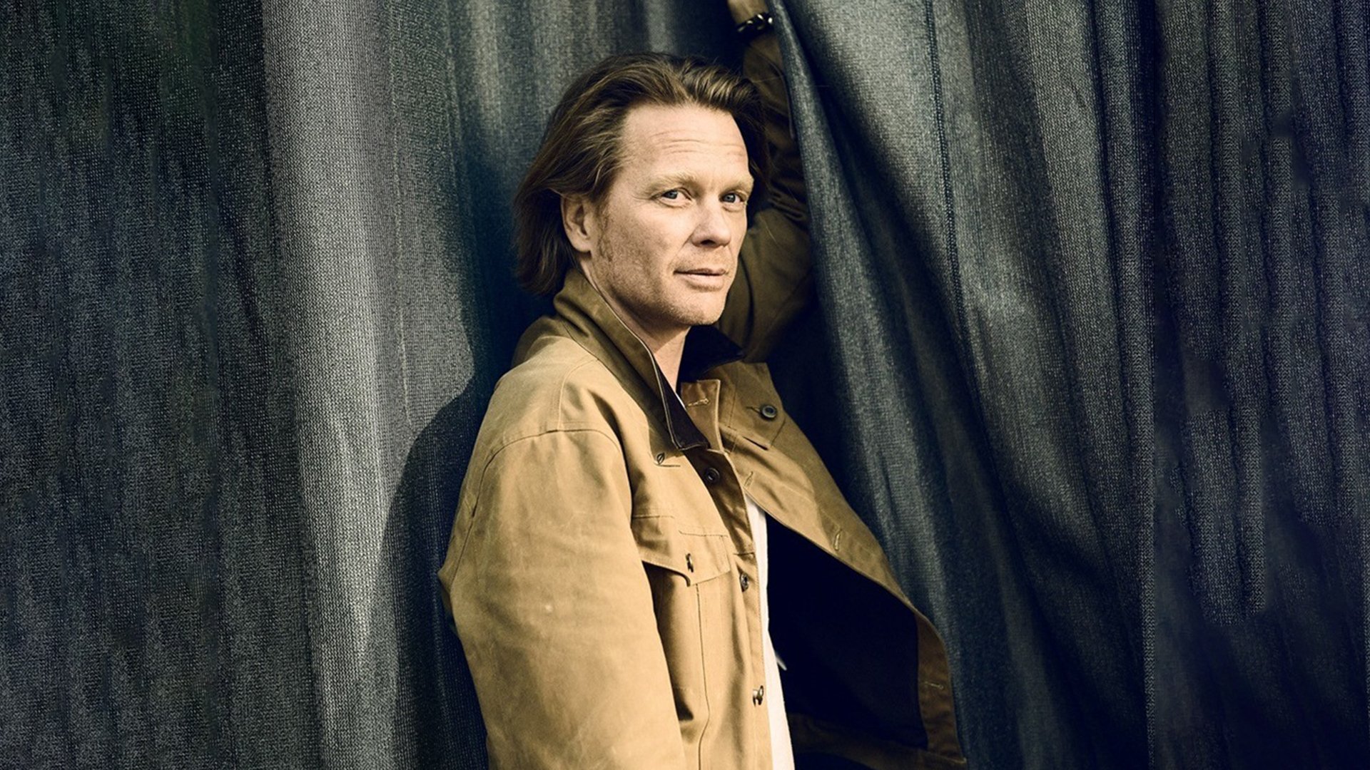 Ein Foto des Künstlers Mike Kraus vor einem grauen Vorhang