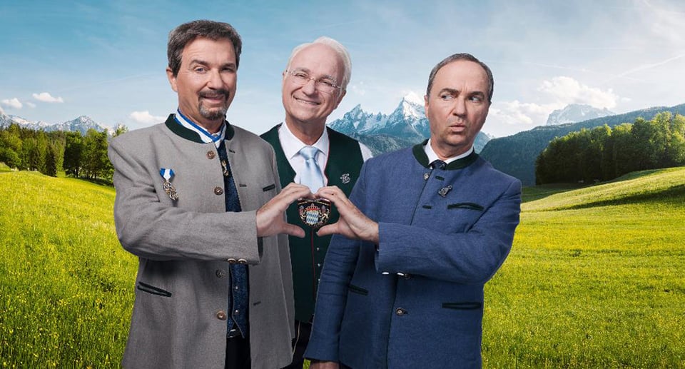 Eine Collage aus drei Fotos, mit Wolfgang Krebs und zwei Darstellern von Markus Söder und edmund Stoiber auf einer Wiese mit Bergen im Hintergrund