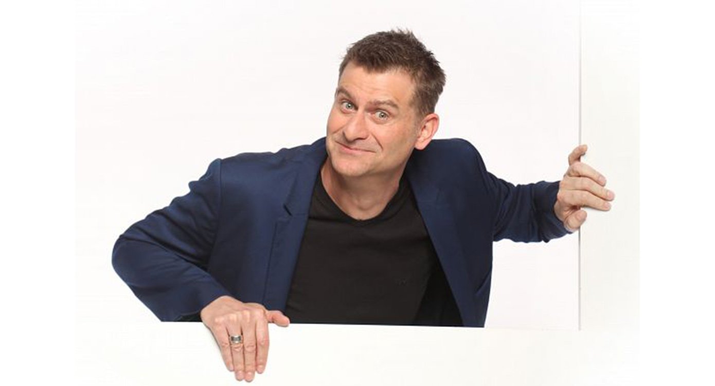 Mann in blauem Sakko, schwarzem Shirt vor weissem Hintergrund