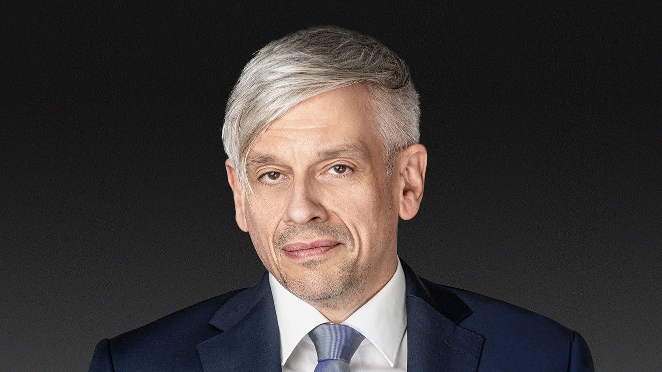 Mathias Tretter in dunkelblauem Anzug mit weißem Hemd vor dunkelgrauem Hintergrund