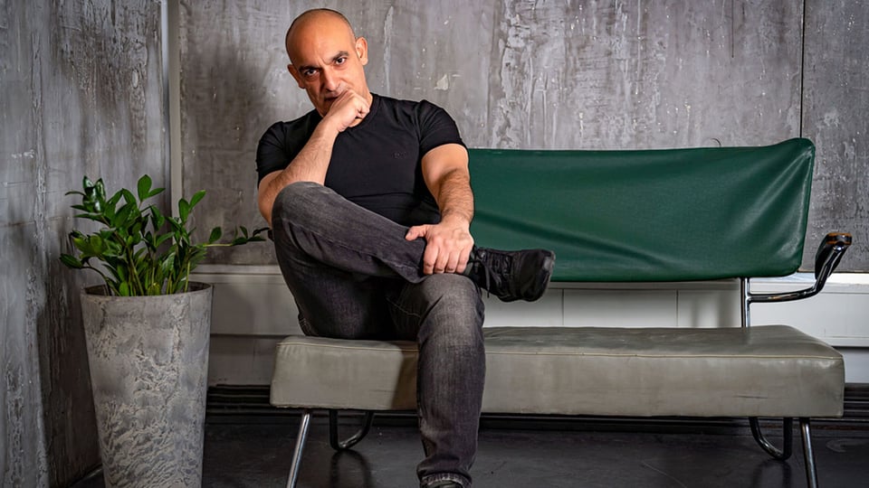 Der Künstler sitzt auf einem grünen Sofa