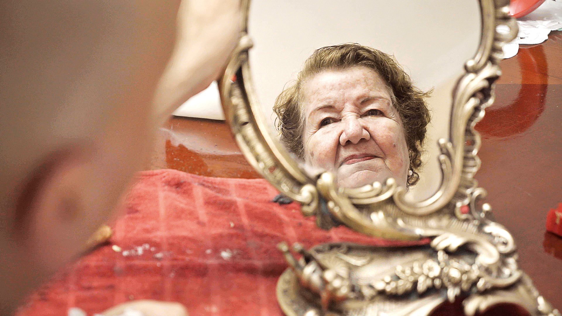 LAFITA – Lateinamerikanische Filmtage München 2025, ein Foto aus dem Film NOSOTROS LOS WOLF, mit dem Gesicht einer Frau, das sich in einem kleinen goldenen Spiegel widerspiegelt