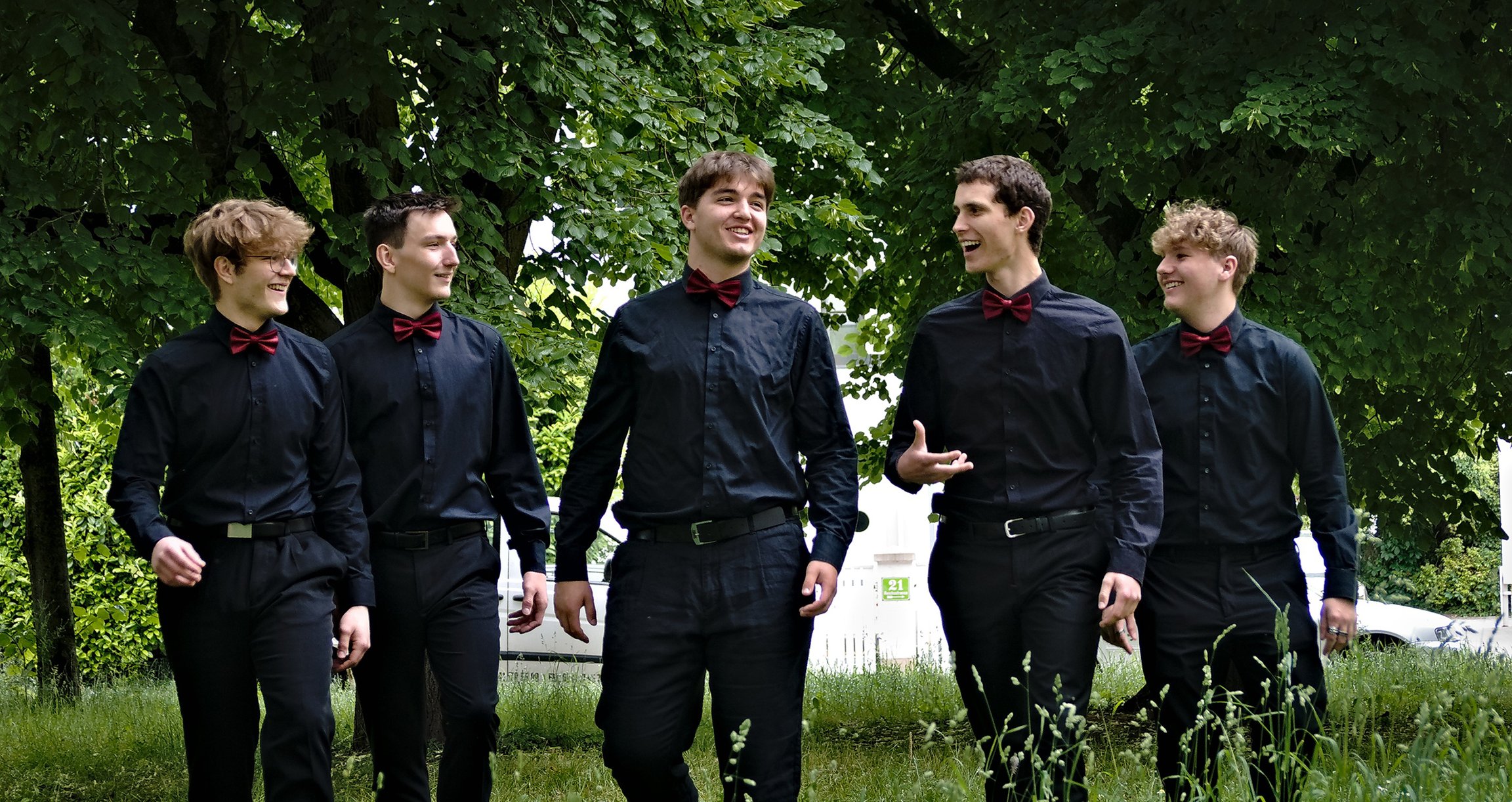 Foto von fünf Jungs mit Hemd und Fliege in einem Park.