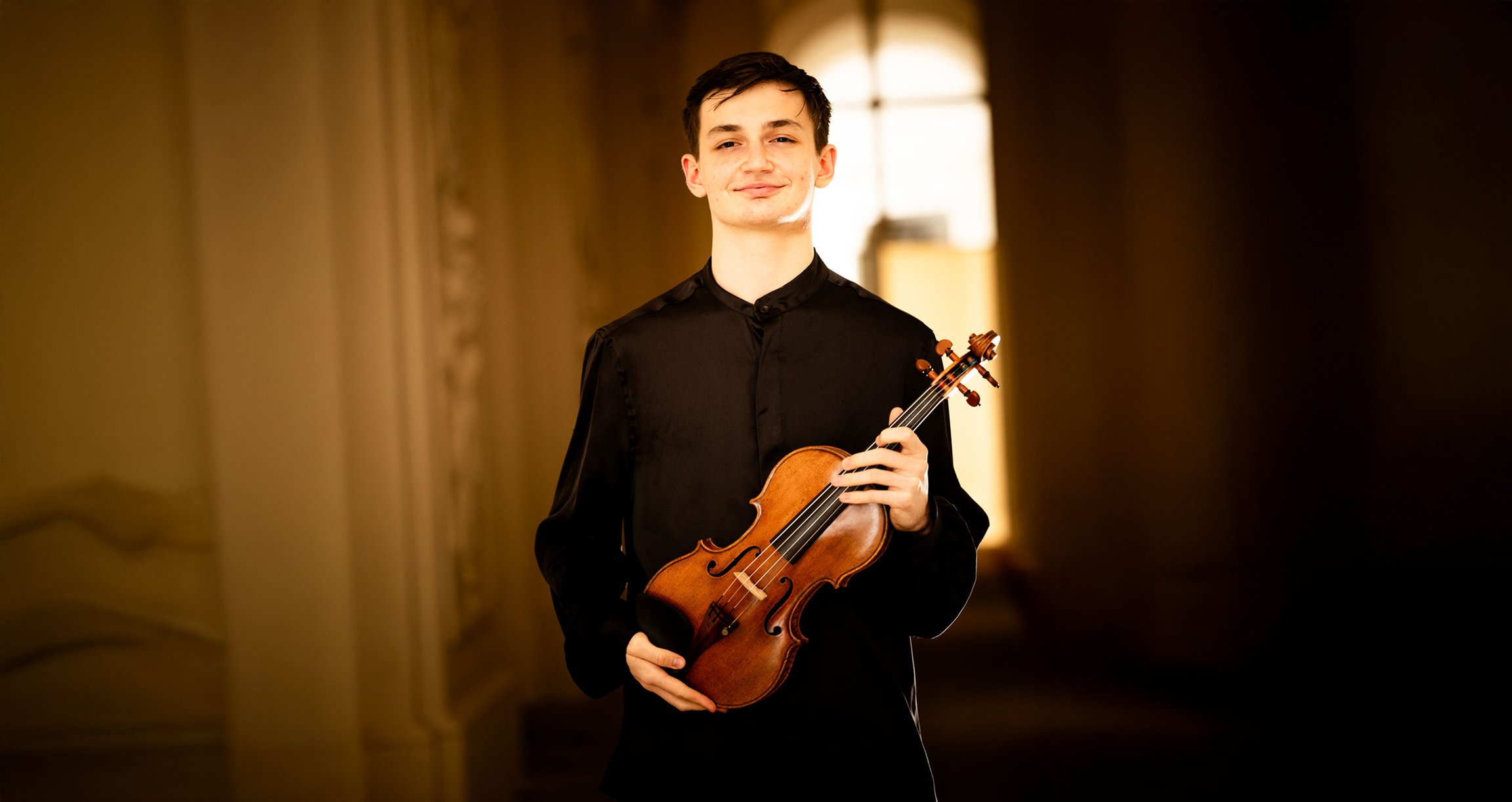Mann in dunkler Kleidung mit Violine