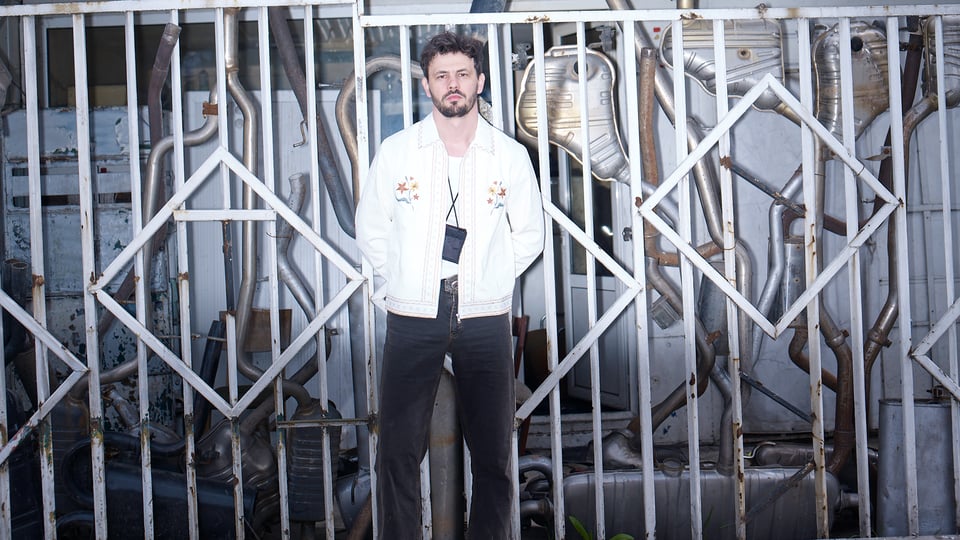 Foto für das Event von BULGARIAN CARTRADER mit dem Künstler vor einem weißen Gitter im Hintergrund.