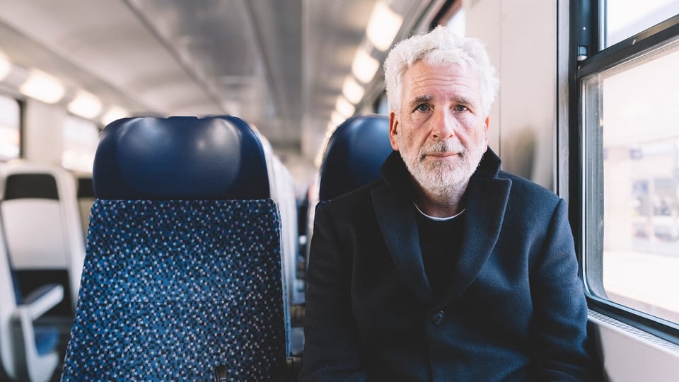 Foto von Dirk Stermann, der in einem Zug sitzt.