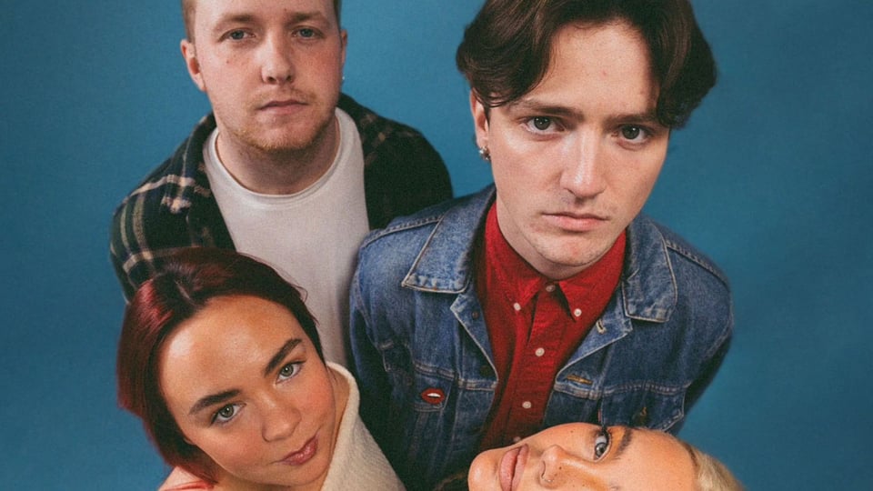 die vier Musiker der Band blickenm nach oben in die Kamera