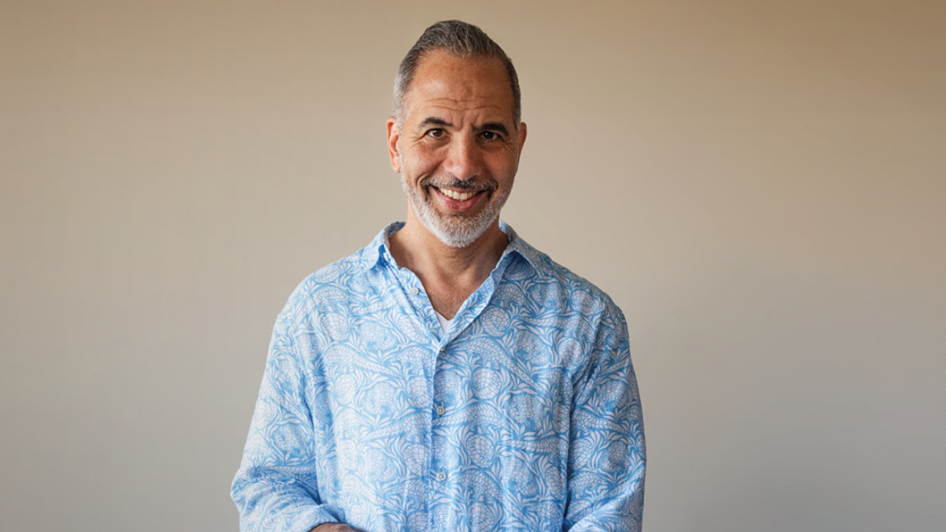 Porträtfoto für das Event von Yotam Ottolenghi: Eine einzelne Person steht vor neutralem, hellem Hintergrund und trägt ein hellblaues, gemustertes Hemd. Die Aufnahme ist frontal, gut ausgeleuchtet und ohne weitere Objekte oder Text im Bild.