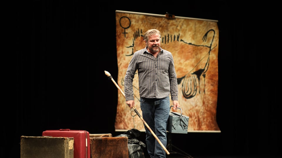 Foto für die Veranstaltung Caveman – ‚Du sammeln, ich jagen!‘ mit dem Künstler und einem Aktenkoffer in der Hand