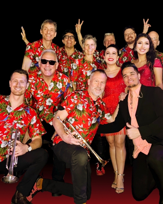 Die Künstler der BigBand mit roten Hemden und teilweise Instrumenten in den Händen