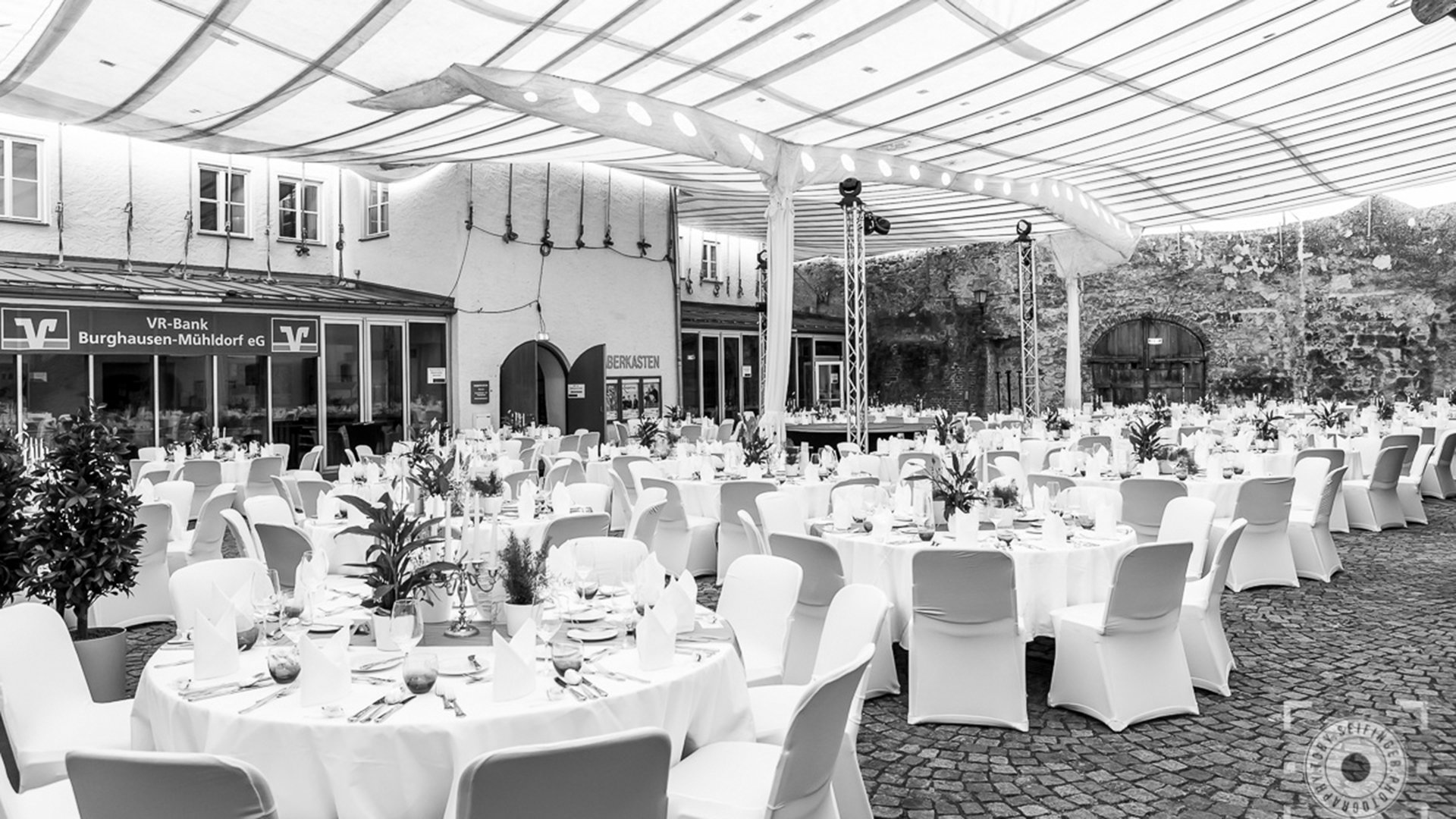 Festlich gedeckter Innenhof zur Veranstaltung 30 Jahre Haberkasten mit runden Tischen, weißen Stühlen und transparenter Überdachung vor historischen Mauern.