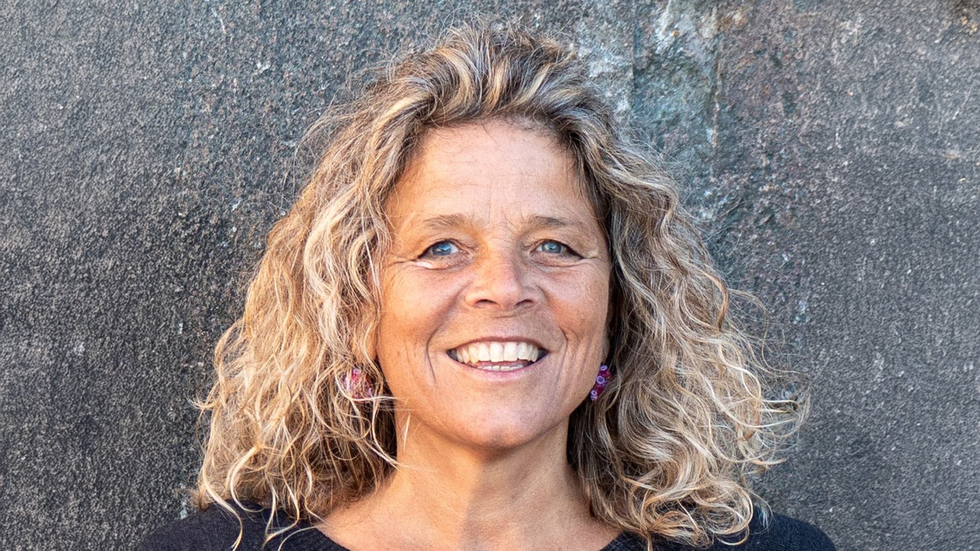 Foto für das Jodelkurs für Einsteiger*innen, mit einer blonden Frau vor einer Steinwand.