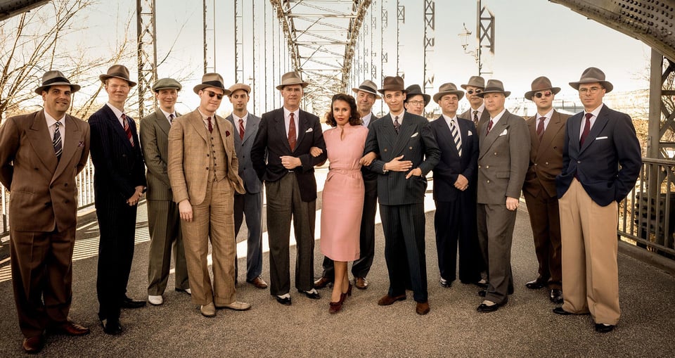 Ein Foto einer Gruppe von Personen in 60er-Jahre-Kleidung auf einer Brücke.