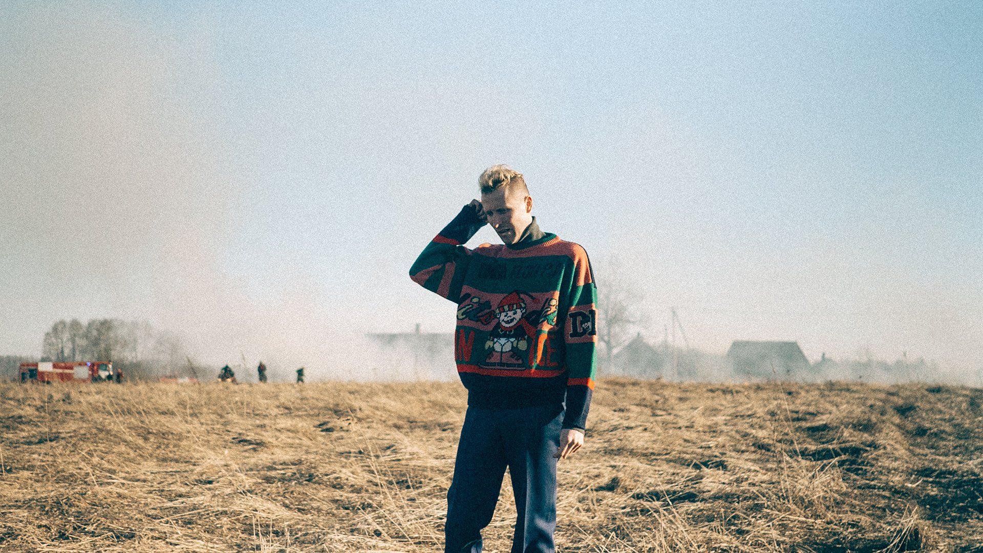 Ein Mann in farbigem Pullover steht auf einem Feld