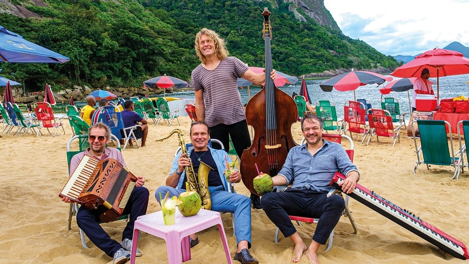 Vier Personen mit Instrumenten an einem Strand