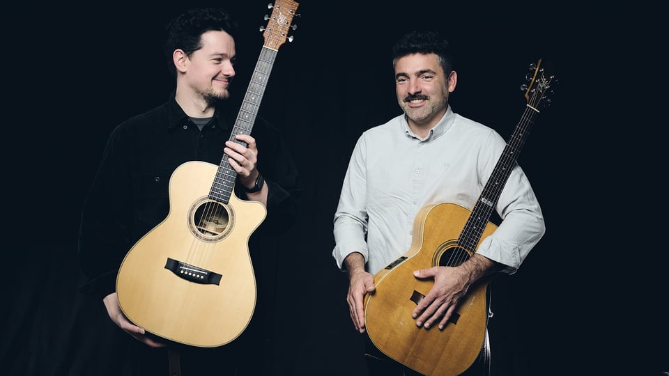 Micha Kern und Jordan Brodie mit Gitarren vor schwarzem Hintergrund
