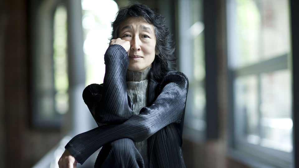 Porträt der Pianistin Mitsuko Uchida in Innenraum vor Fensterfront.