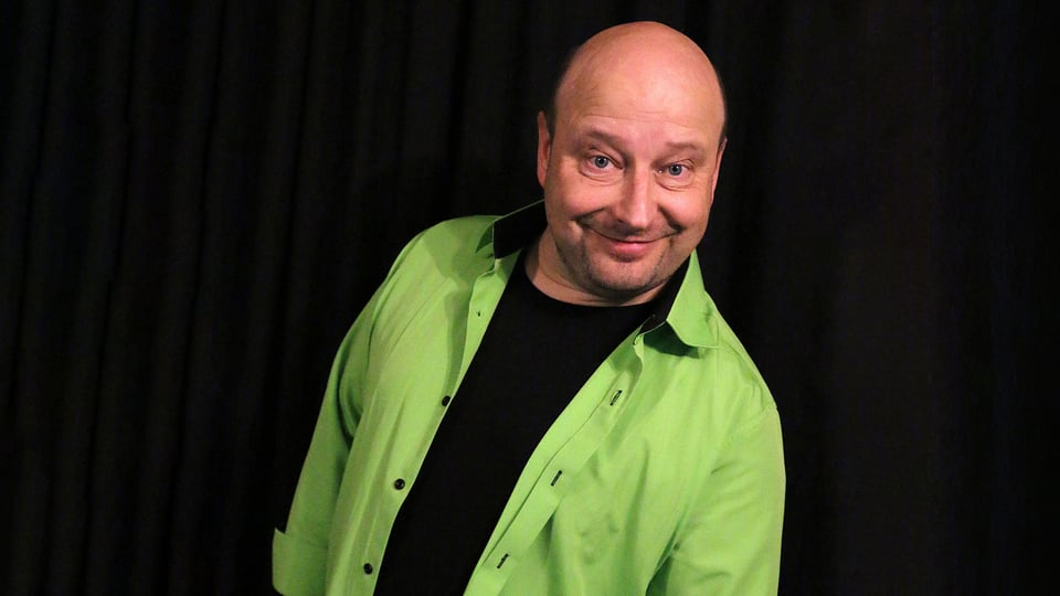 Pressefoto von Wolfgang „WUFFI“ Kamm vor schwarzem Hintergrund, mit grünem Hemd.