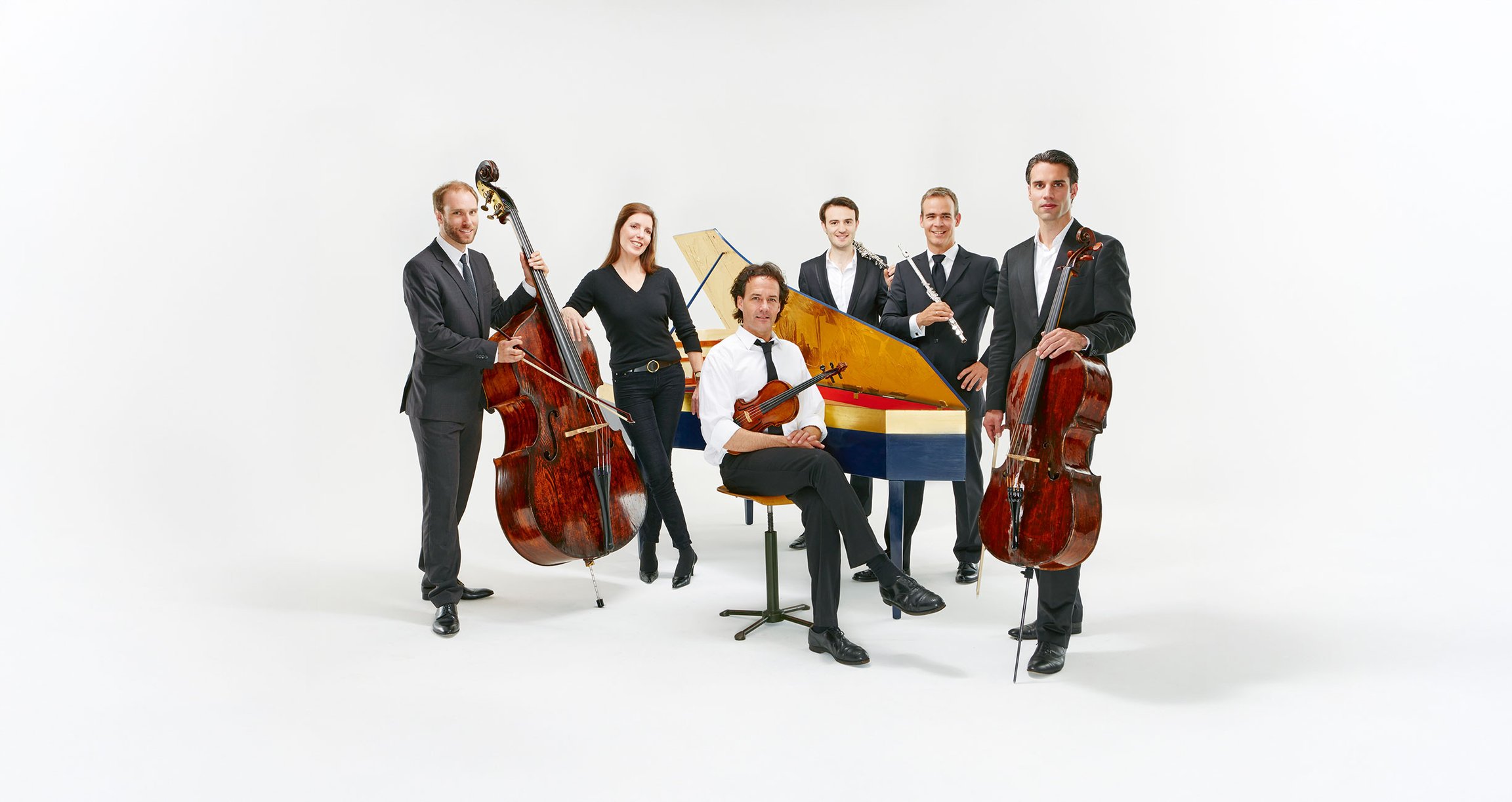 Sechs Personen mit Instrumenten vor hellem Hintergrund