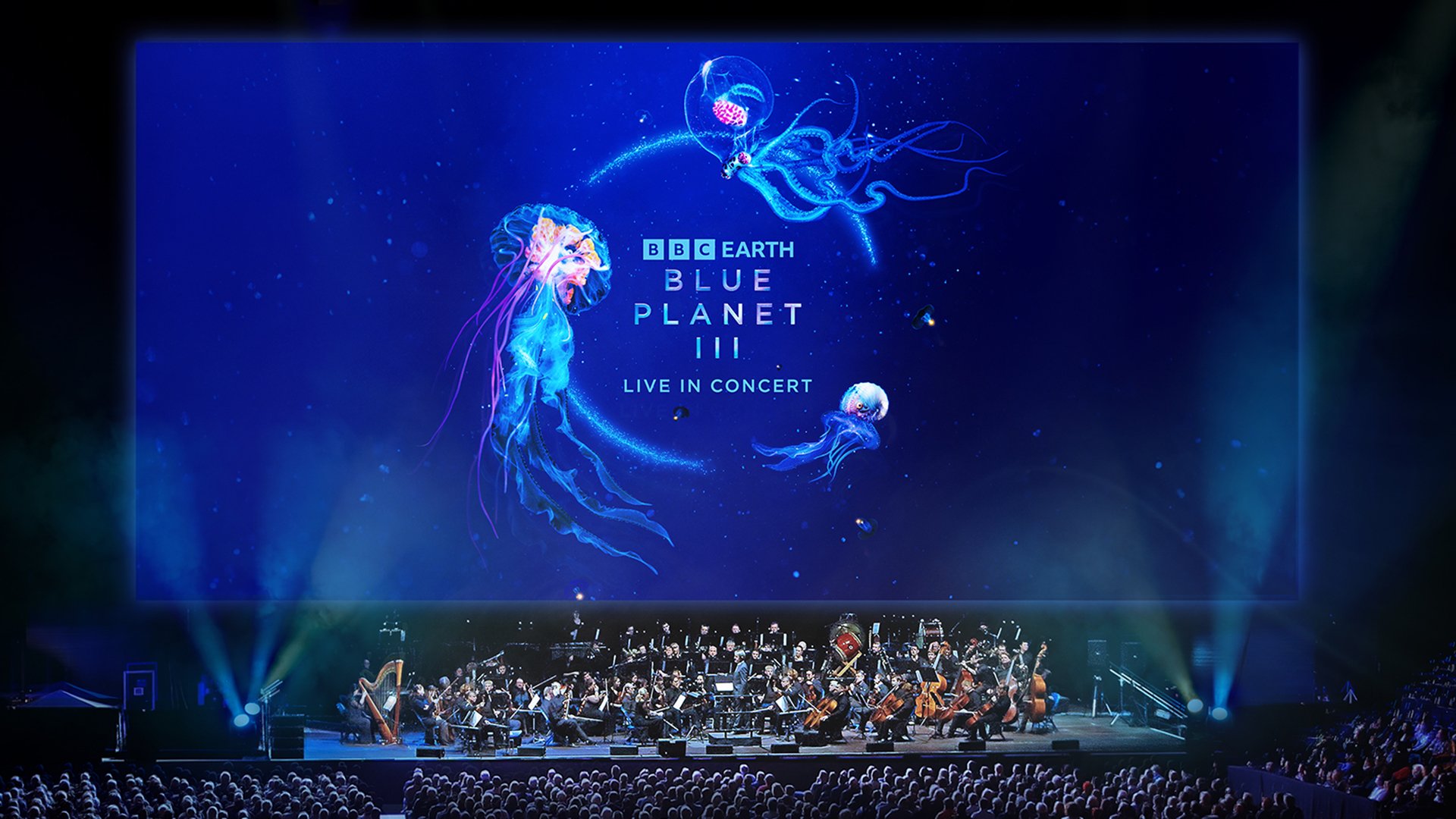 Plakat BBC Earth Blue Planet III Live in Concert mit großem Symphonieorchester vor Publikum auf einer Bühne, darüber eine riesige Leinwand mit Quallenmotiven und dem Schriftzug BBC Earth Blue Planet III Live in Concert auf tiefblauem Hintergrund.