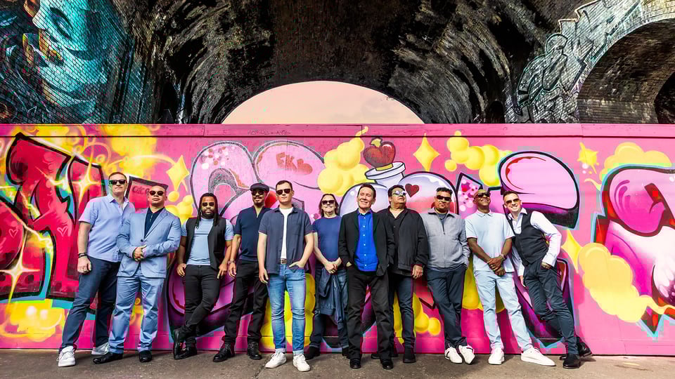 UB40 vor einer Wand mit Graffiti – Gruppenfoto der Band beim Event.