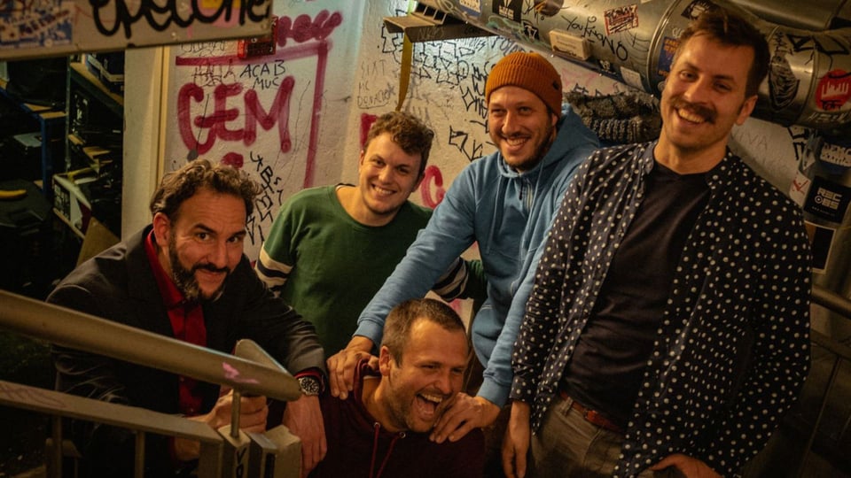 Die Gruppe Rationalversammlung mit fünf Personen steht auf einer mit Graffiti bedeckten Treppe in einem schummrig beleuchteten, urbanen Umfeld