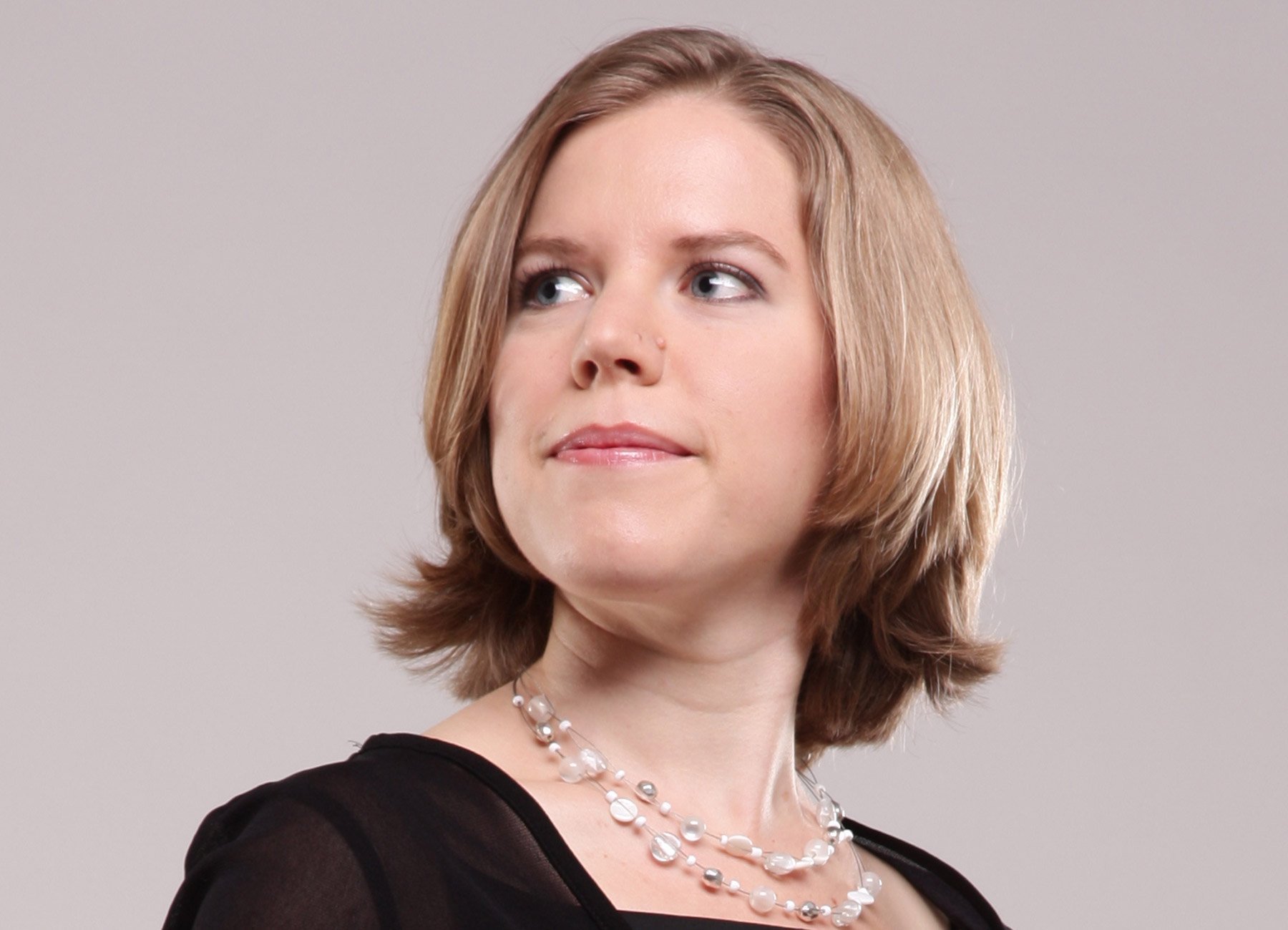 Portrait von blonder Dame in schwarzem Kleid mit Perlenkette