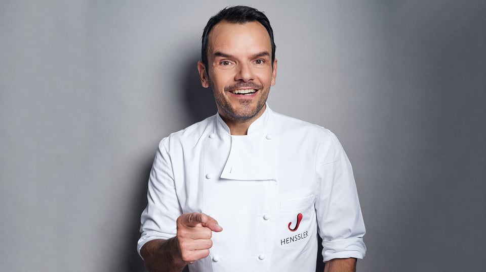 Auf dem Bild ist Steffen Henssler vor einem grauen Hintergrund zu sehen