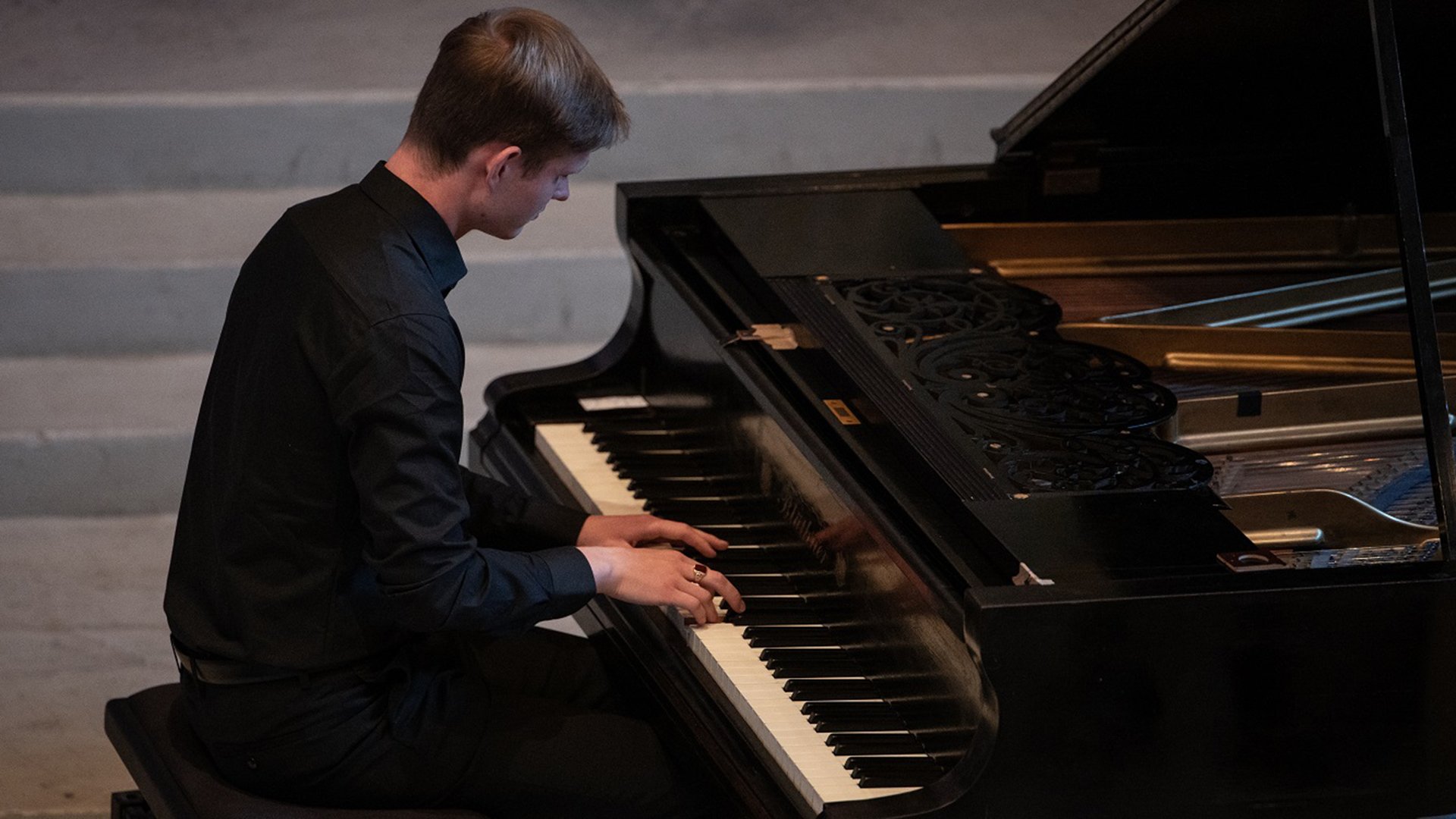 Der Künstler in dunkler Kleidung am Konzertflügel