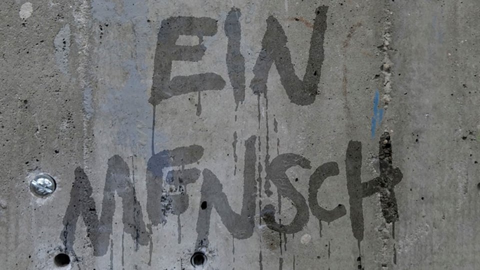 Musiktheater im Reaktor 2026: Schriftzug „Ein Mensch“ auf einer Betonwand.