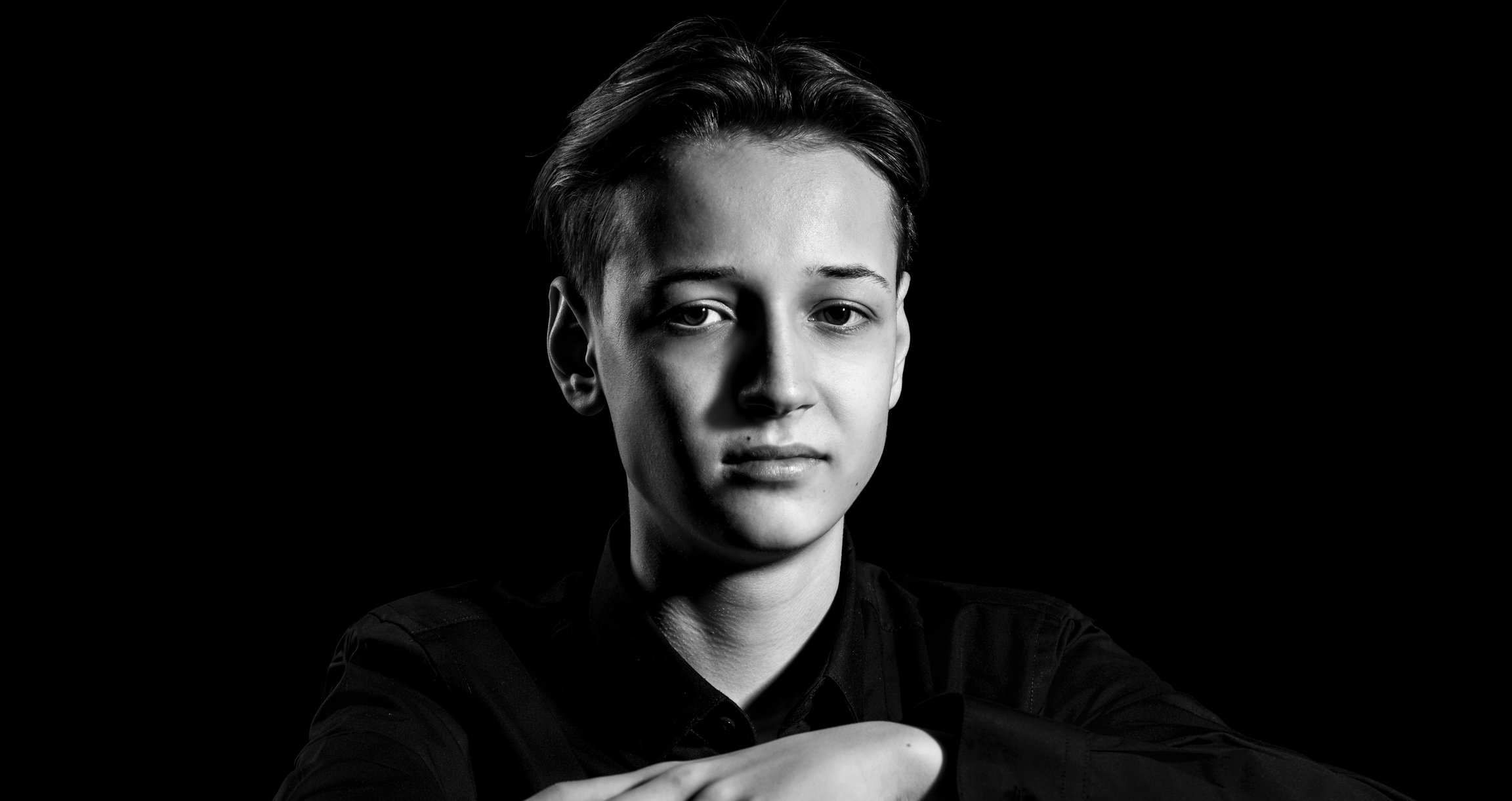 Portrait einer Person in schwarz-weiß vor dunklem Hintergrund
