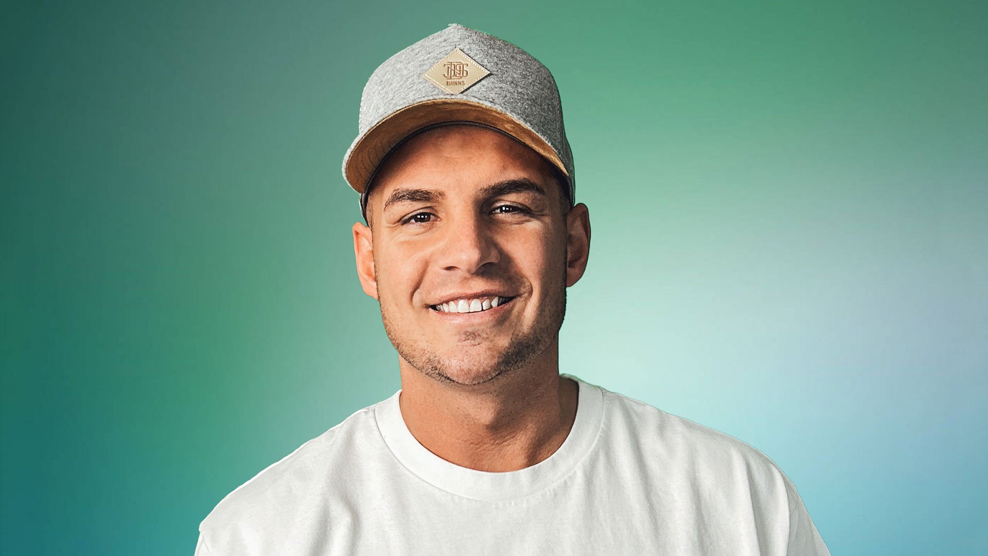 Foto für das Event Pietro Lombardi & Band mit dem Künstler mit einer Kappe vor grünem Hintergrund