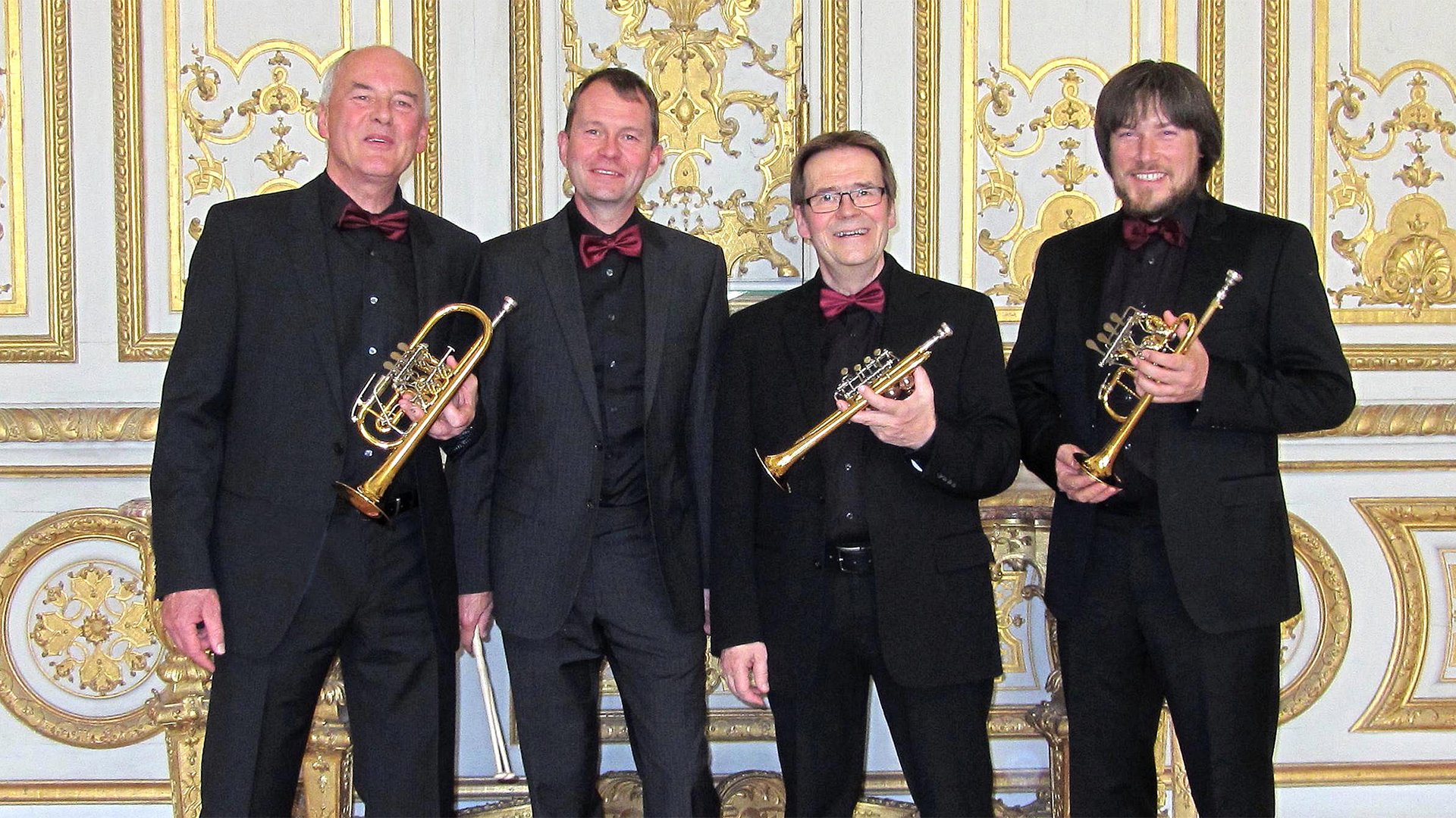 Vier Künstler mit ihren Instrumenten vor festlicher Kulisse