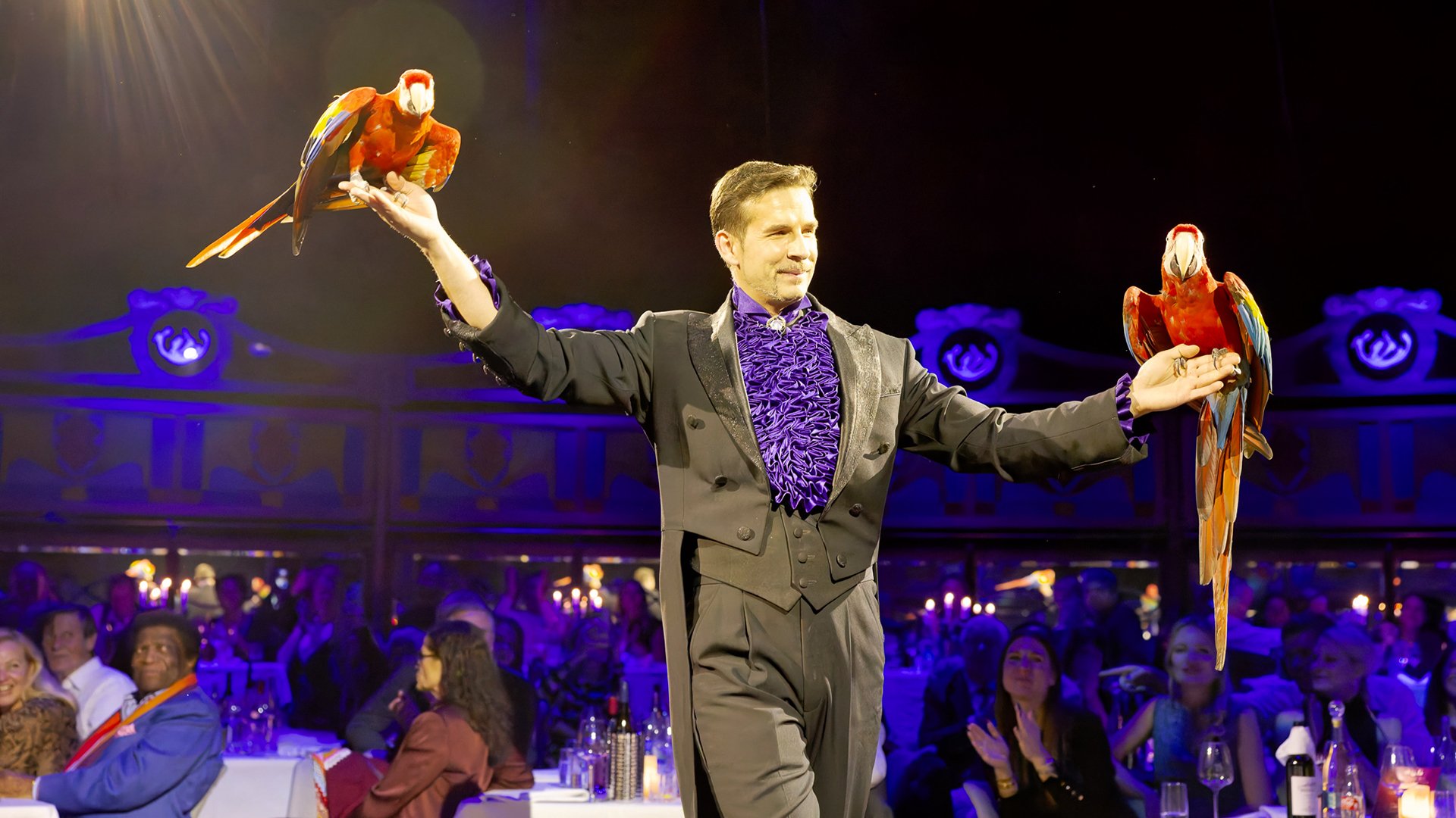 Ein Darsteller mit zwei Papageien auf den Händen