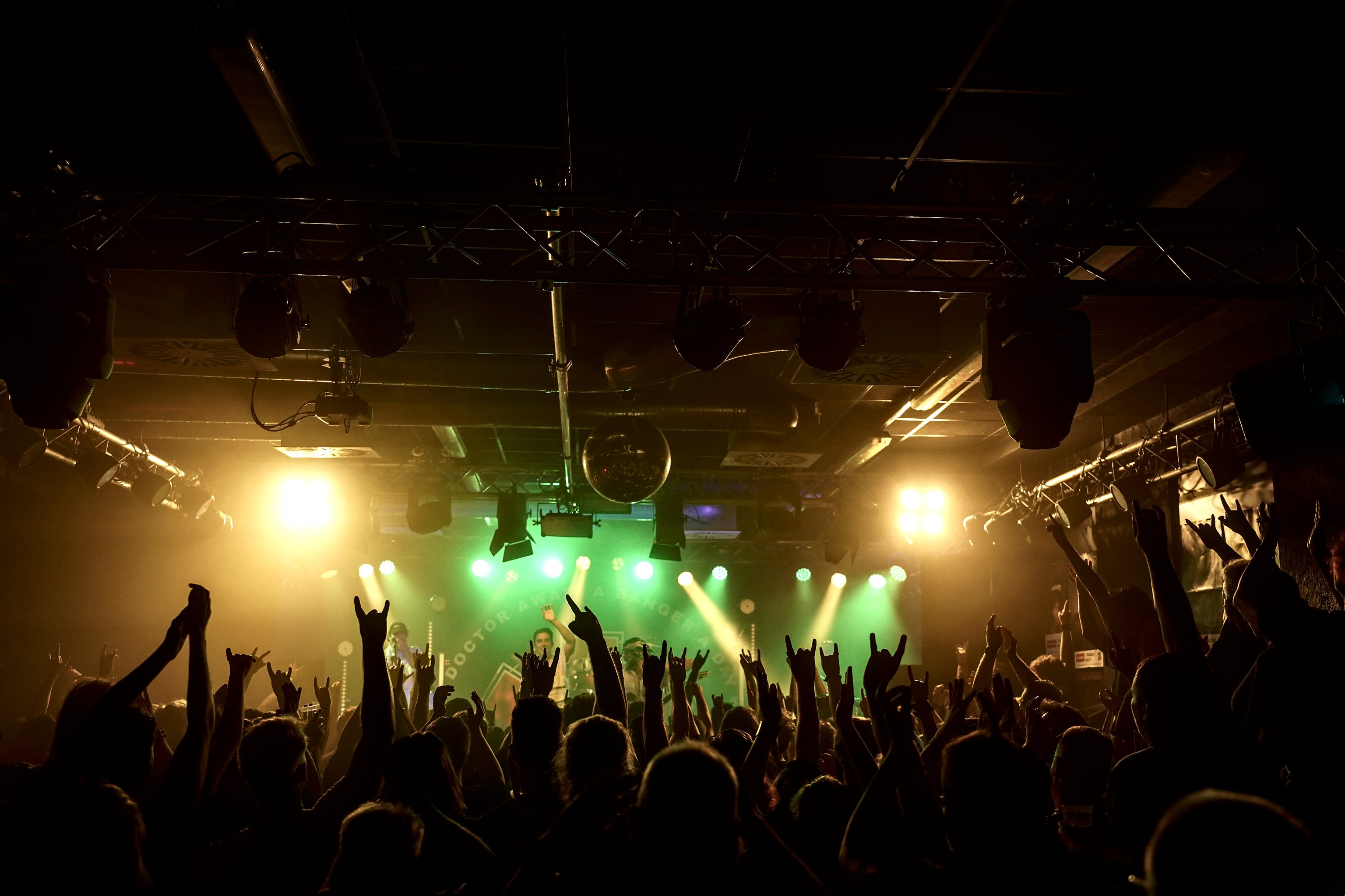 Aufnahme aus der Crowd im Feierwerk. Im Hintergrund die Bühne, auf der gerade ein Act performt.