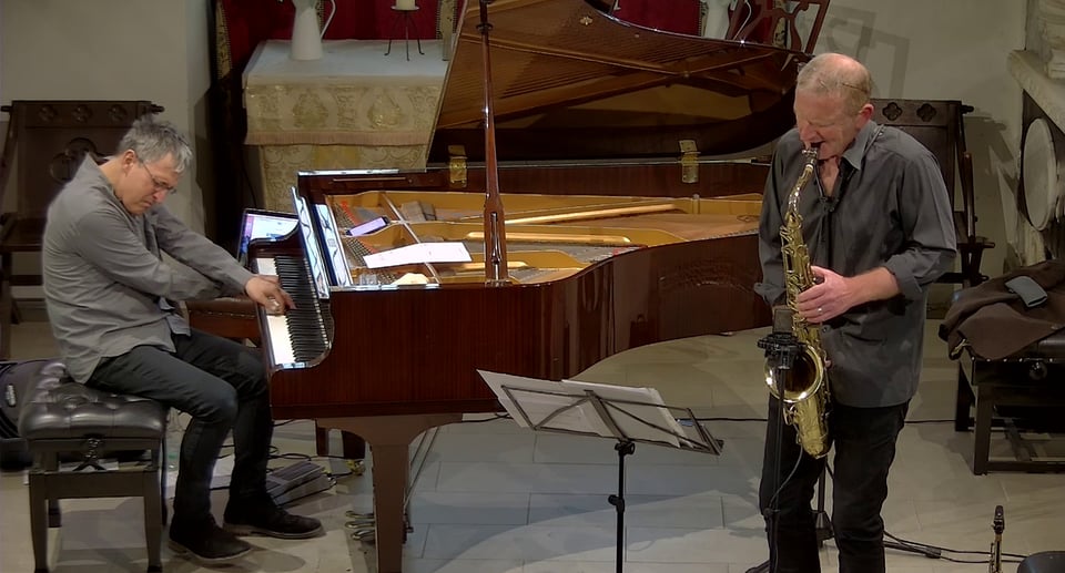 Foto von zwei Männern, die Instrumente spielen, und einer mit einem Klavier.