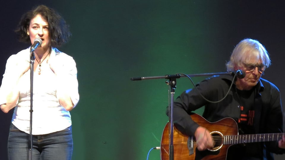 Foto für die Veranstaltung A Gift of Roses mit beiden Künstlern auf der Bühne, sie singend und er auf einem Stuhl sitzend mit Gitarre