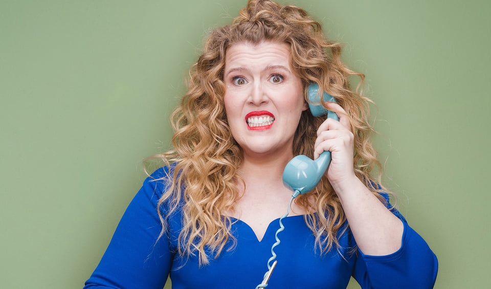 Franziska Wanninger mit Telefon in der Hand vor grünem Hintergrund – offizielles Veranstaltungsbild zum Kabarettprogramm „Wenn du wen brauchst, ruf mich nicht an“.