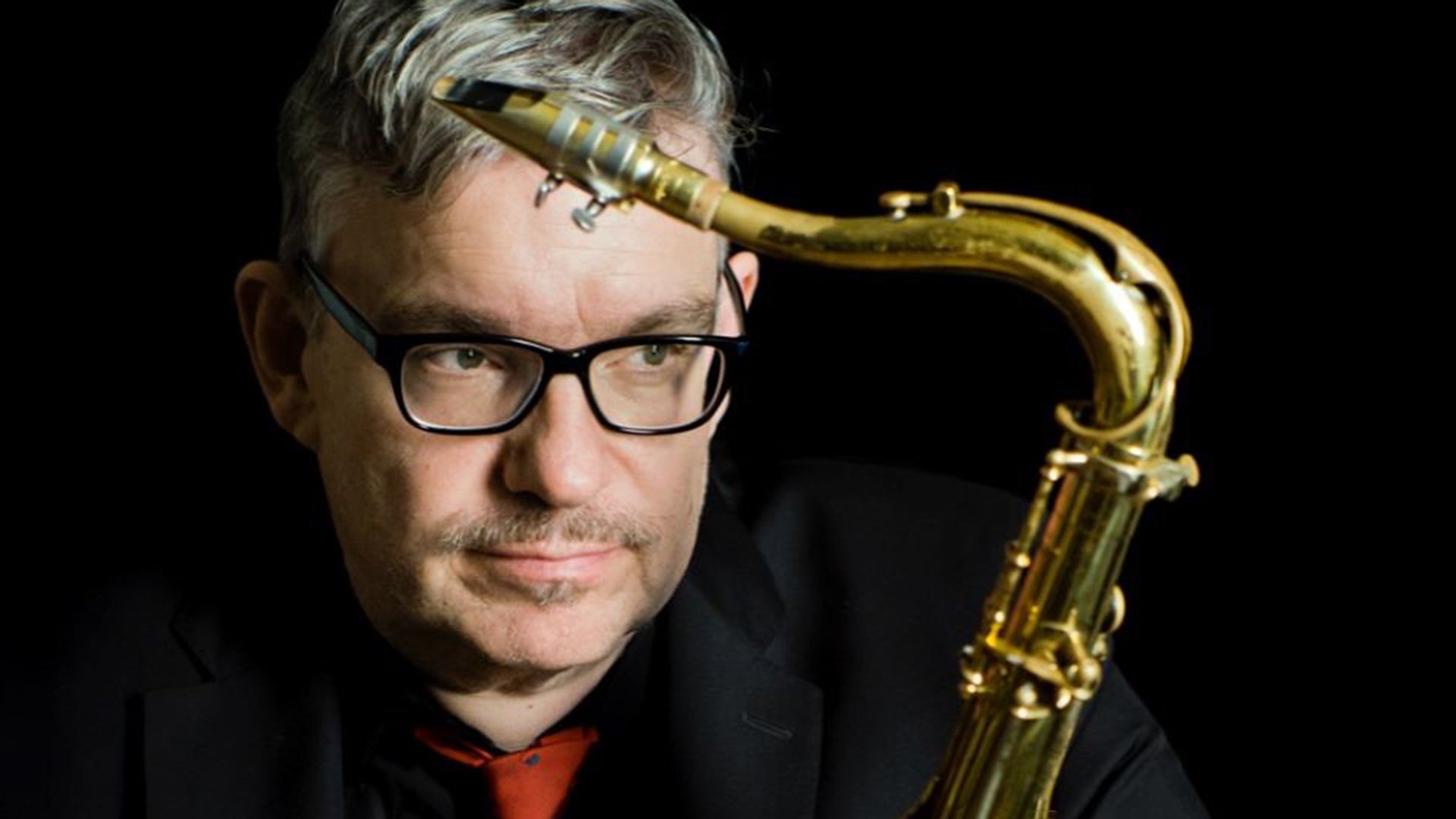 Foto für das Event „Johannes Enders – Michael Wollny Duo“ mit dem Gesicht des Künstlers und einem Saxophon vor schwarzem Hintergrund