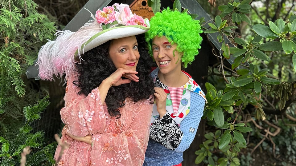 Foto für das Event „KiKolino und KiKilina entdecken den Schatz der Oper“ mit den beiden verkleideten Künstlern und einer Pflanze im Hintergrund.