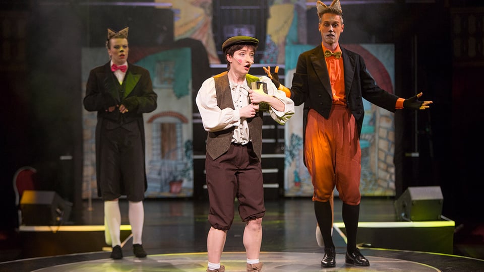 Bühnenszene mit drei Darstellern des Kindermusicals Pinocchio mit farbiger Bühnenkulisse