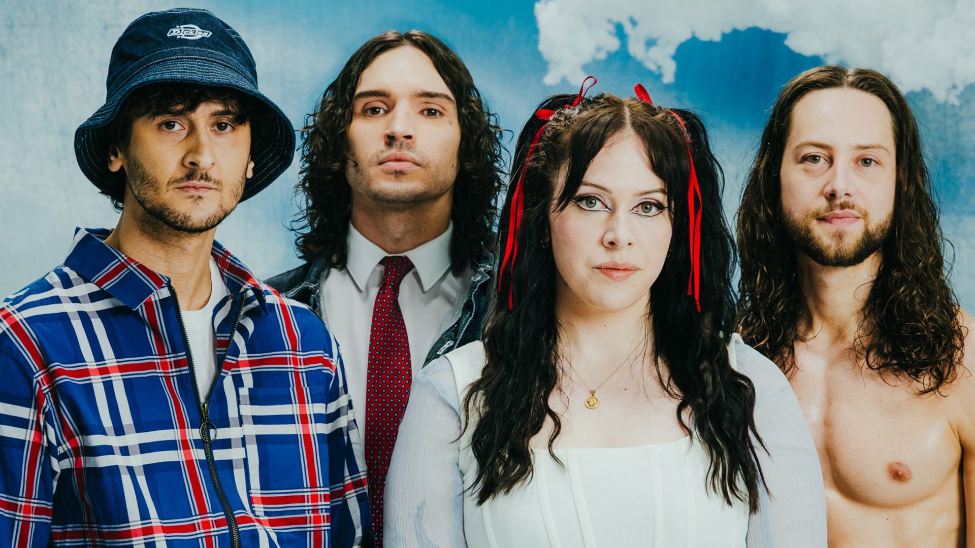Bandfoto von Unpeople mit vier Bandmitgliedern vor blauem Hintergrund mit Wolkenmotiv, eine Person mit Hut und karierter Jacke, eine Person mit Krawatte, eine Person in weißem Oberteil mit roten Schleifen im Haar sowie eine Person mit langen Haaren