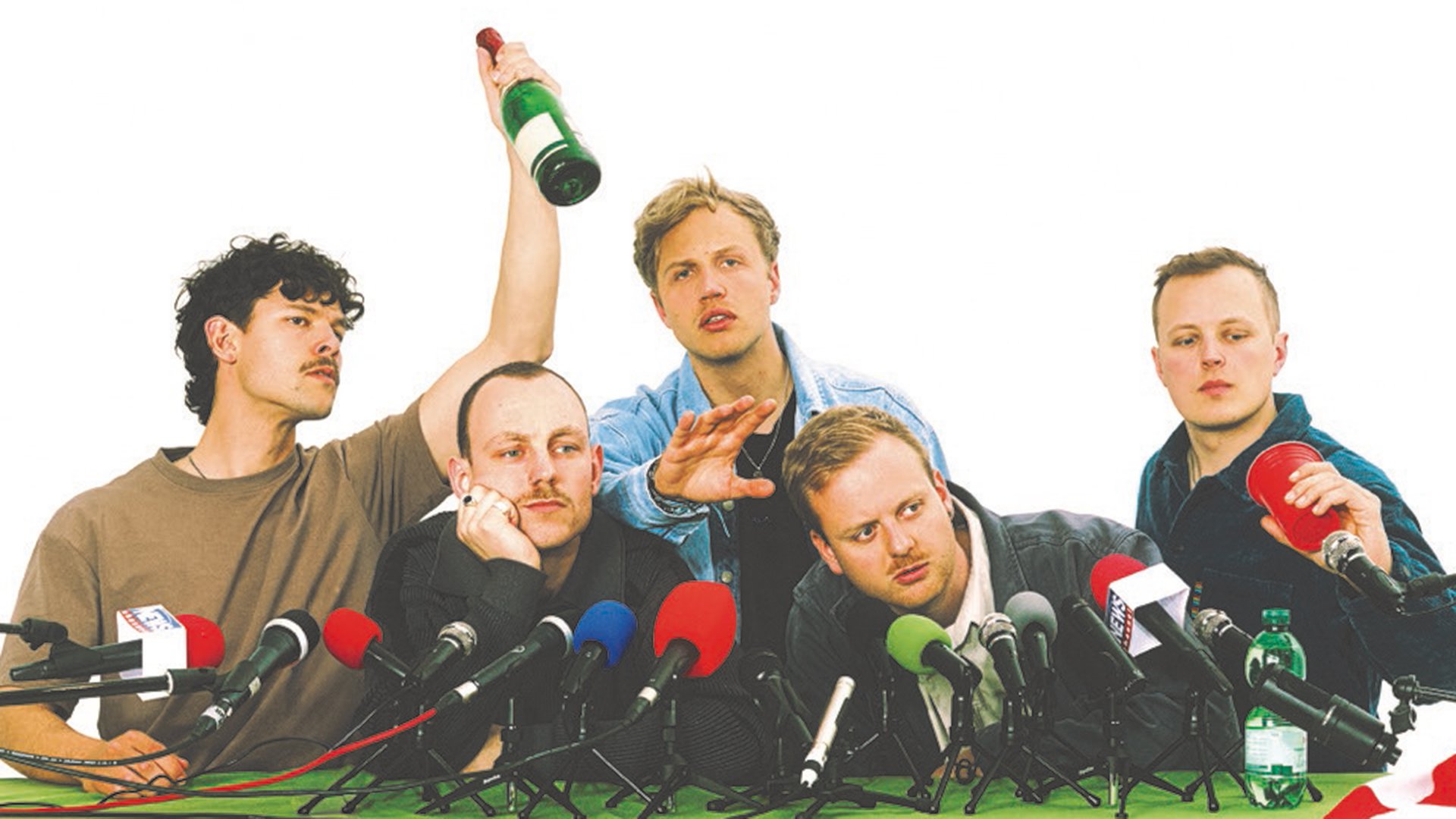 Die Musiker von Kaffkiez vei einer Pressekonferenz mit mehreren farbigen Mikrofonen 