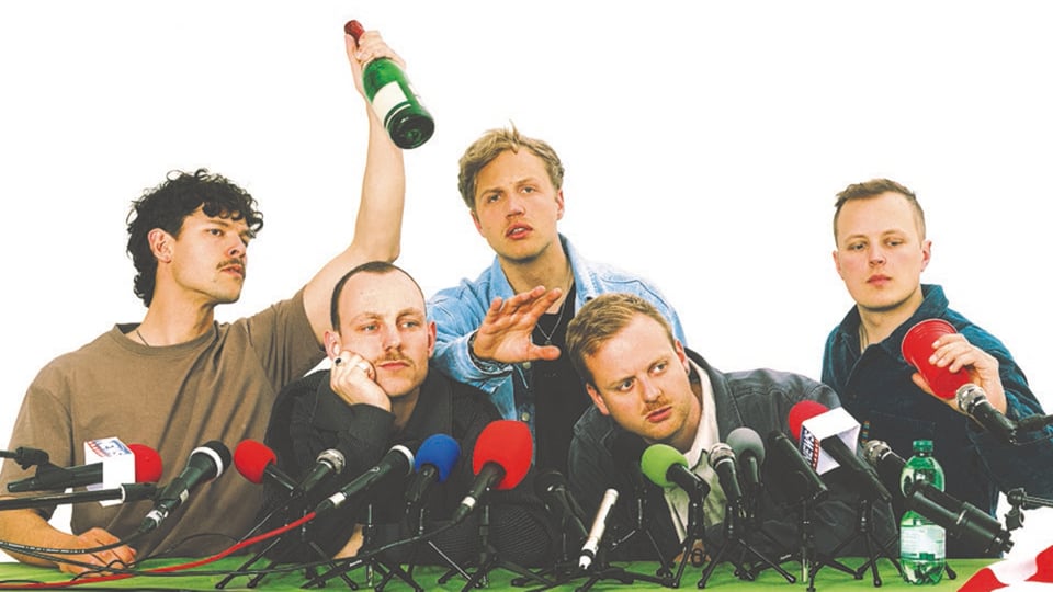 Die Musiker von Kaffkiez vei einer Pressekonferenz mit mehreren farbigen Mikrofonen 