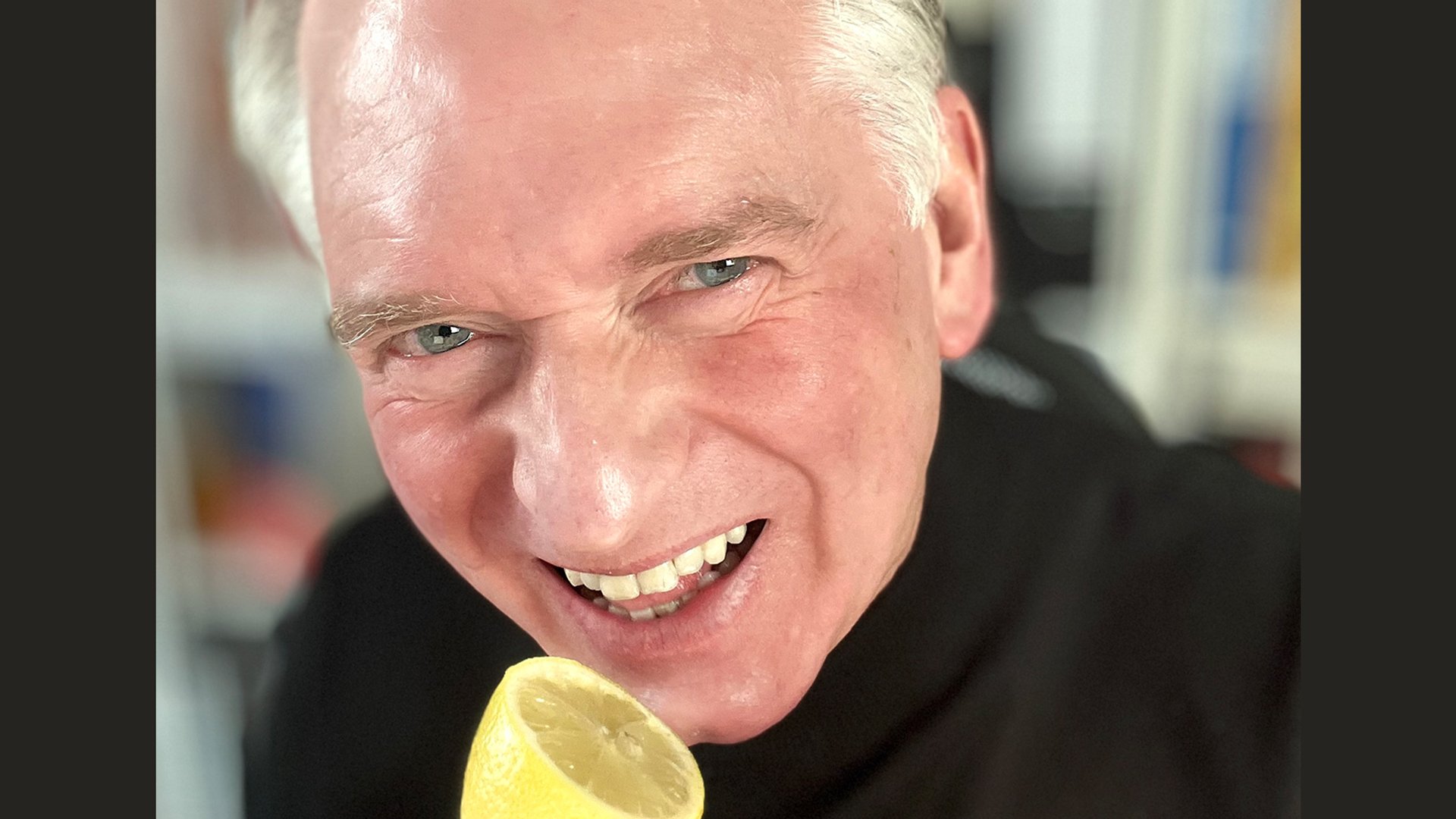 Der Kabarettist in schwarzem Pullover macht eine Grimasse und hält sich eine aufgeschnittene Zitrone an den Mund