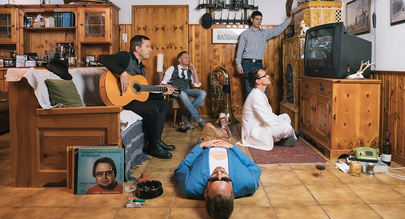Foto eines Wohnzimmers mit fünf Männern, die fernsehen, aber jeder in einer anderen Position